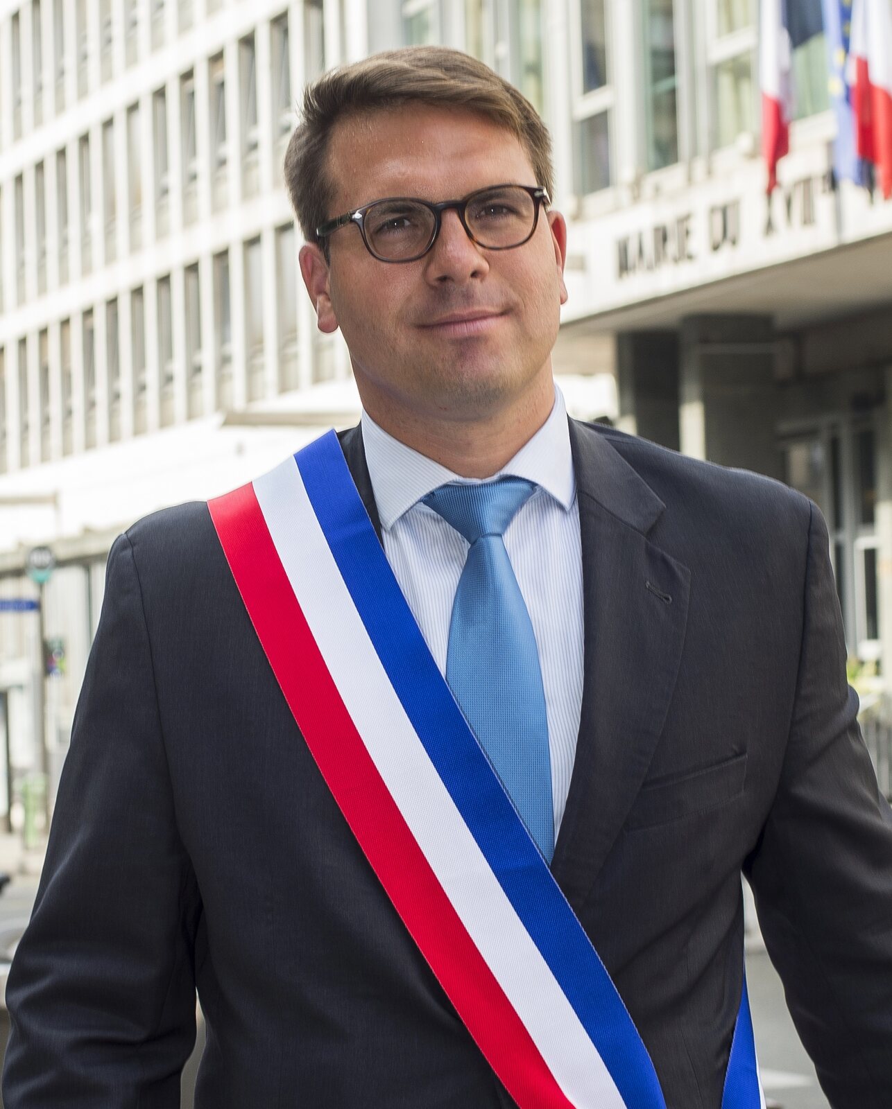 Geoffroy Boulard portant l’écharpe de maire devant la mairie du 17e